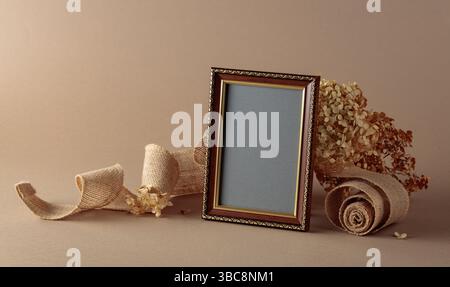 Cadre photo vide, ruban de toile de jute et fleurs d'hortensia séchées sur fond beige. Placez votre image dans le cadre. Copier l'espace. Banque D'Images