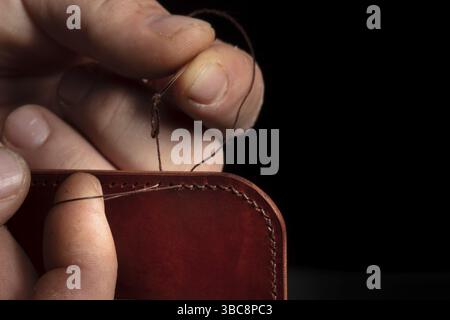 Fabrication de portefeuilles en cuir. Les mains du maître cousent un produit en cuir Banque D'Images