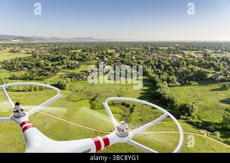 Drone Quadcopter volant au-dessus du paysage des prairies avec zone résidentielle de la ville à distance - image composite numérique Banque D'Images
