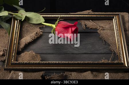 Dans un beau cadre, des morceaux de toile et une rose rouge sur fond de bois Banque D'Images