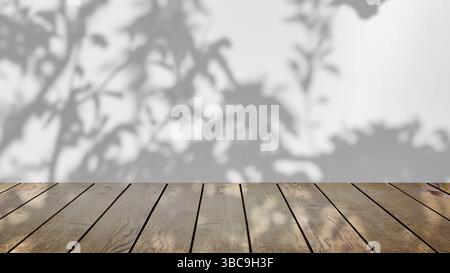 ombre des arbres se balançant doucement dans la brise, sur un fond blanc avec une table en bois. Banque D'Images