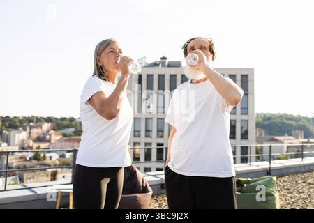 Couple mature restant hydraté après une activité extérieure en milieu urbain Banque D'Images