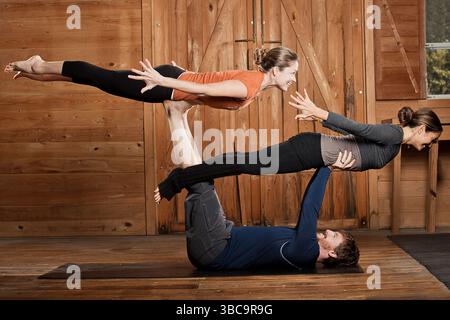 Deux femmes et un homme équilibrant l'Acroyoga ou le yoga volant Banque D'Images