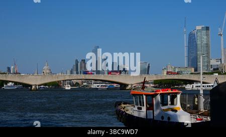 Waterloo Bridge traversant la Tamise avec l'horizon de Londres, le centre financier et St.Paul`s avec des bateaux de premier plan par temps clair. Banque D'Images