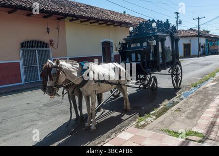 Cheval antique tiré corbillard attendant en préparation pour des funérailles dans une rue devant une organisation funéraire. Grenade, Nicaragua. Banque D'Images