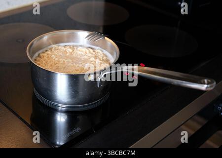 Stockholm, Suède - 8 mai 2025 : pot en acier inoxydable avec des nouilles instantanées bouillant sur une cuisinière électrique dans une cuisine moderne pendant un moment de cuisson maison Banque D'Images