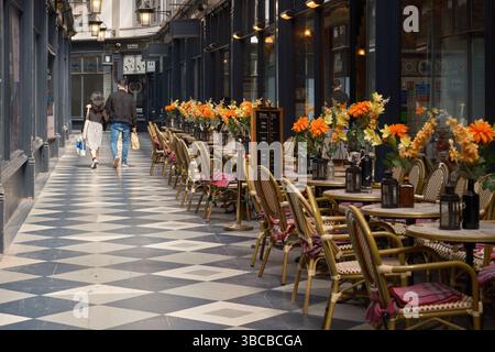 Des tables de café ornées de fleurs bordent la passerelle carrelée de Castle Arcade à Cardiff, au pays de Galles, tandis que les clients se promènent dans les boutiques victoriennes Banque D'Images