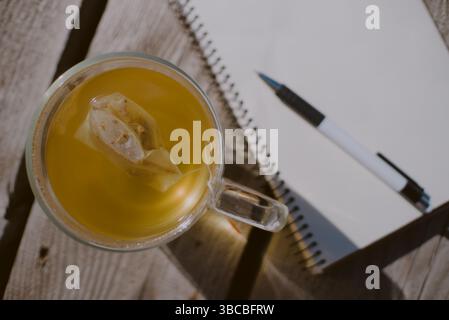 Vue de haut en bas d'une tasse de thé ensachée et journal de papier blanc ouvert avec des pages vides et un stylo Banque D'Images