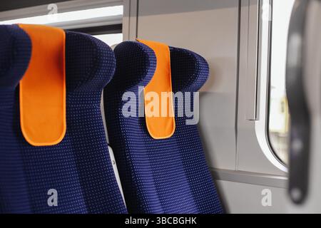 Design intérieur moderne des trains. Sièges passagers confortables. Rembourrage bleu avec appuie-tête orange. Transports publics en Europe. Train vide. Banque D'Images
