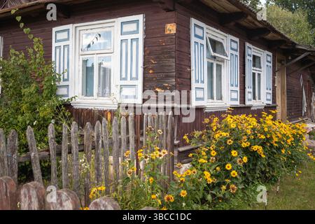 Une maison avec une clôture de piquet blanche et un jardin de fleurs devant elle. La maison est vieille et a une sensation rustique à elle Banque D'Images