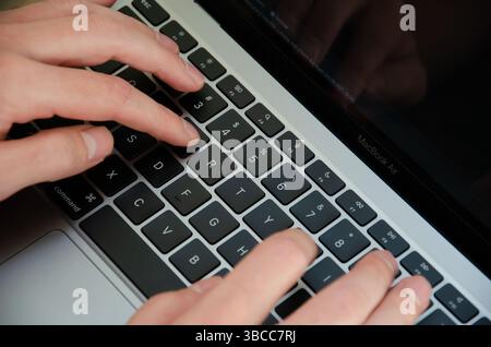 Kiev, Ukraine - 5 septembre 2021. Un homme caucasien utilise MacBook Air M1. La personne travaille sur le dernier ordinateur portable Apple. Vue de dessus mains sur le clavier de l'appareil. Banque D'Images