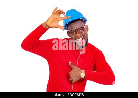 jeune homme heureux ingénieur de construction portant un casque de sécurité bleu et faisant des gestes avec les doigts. Banque D'Images