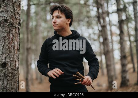 Jeune individu dans une forêt rassemblement bâtons sur une sortie hivernale Banque D'Images