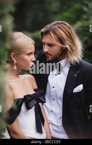Élégant jeune beau couple nouveau-lywed posant au mariage dans le beau parc vert Banque D'Images