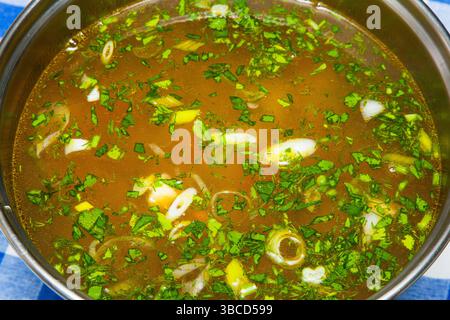 Soupe avec boulettes de viande, légumes, herbes et oeufs dans une casserole gros plan. Banque D'Images
