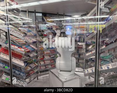 Minsk, Biélorussie - 29 avril 2025 : dans une pharmacie moderne animée, un commis robot se tient au centre, entouré d'étagères remplies de divers médicaments Banque D'Images