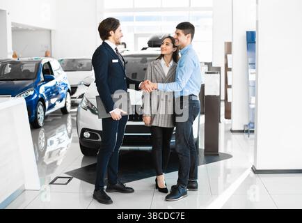 Manager en train de se faire le conseiller auprès des jeunes acheteurs après une transaction réussie Banque D'Images