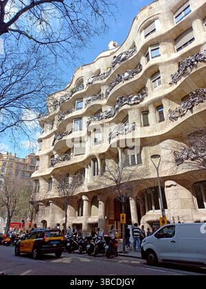 Barcelone Catalogne Espagne. 10 avril 2025. Extérieur en pierre courbée de la Casa Milà de Gaudí avec balcons en fer forgé et colonnes sculpturales le long d'un bustli Banque D'Images
