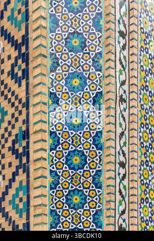 Une colonne de la Madrasah Nadir Divan Begi à Boukhara, en Ouzbékistan, est recouverte d'une mosaïque géométrique bleue, jaune et blanche en motifs islamiques. Banque D'Images