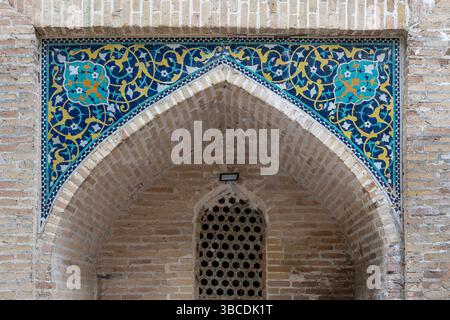 Le carrelage bleu et jaune avec des motifs floraux décore le portail arqué de la Madrasah Nadir Divan Begi à Boukhara, Ouzbékistan. Banque D'Images