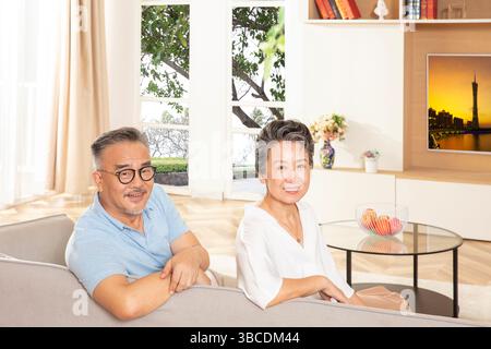 Le couple âgé est assis sur le canapé à regarder TV​ Banque D'Images