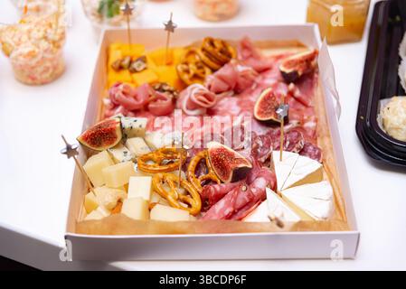 Un plateau de charcuterie gourmand avec assortiment de fromages, charcuteries, figues, bretzels et noix, parfait pour les fêtes ou la restauration haut de gamme. Banque D'Images