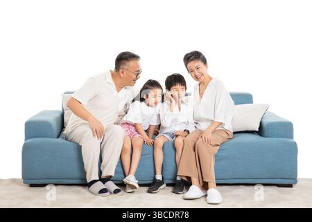 quatre générations (grands-parents et petits-enfants) sur le canapé faisant des appels téléphoniques Banque D'Images
