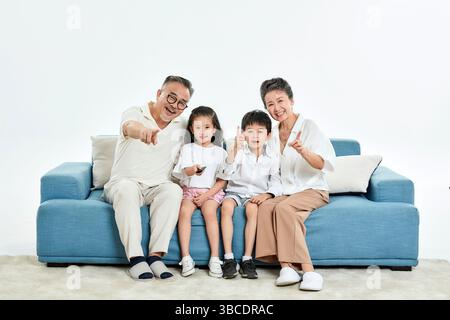 Quatre générations (grands-parents et petits-enfants) regardant la télévision sur le canapé Banque D'Images