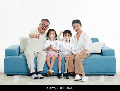 Quatre générations (grands-parents et petits-enfants) regardant la télévision sur le canapé Banque D'Images