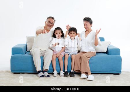 Quatre générations (grands-parents et petits-enfants) regardant la télévision sur le canapé Banque D'Images