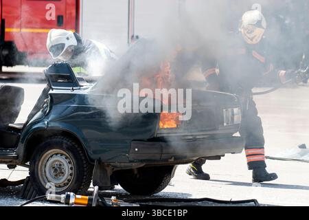 Les pompiers attaquent un feu de propane. Pompier éteignant le feu. Pompiers éteignant un incendie de voiture. Banque D'Images