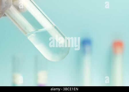 Scientifique avec réaction chimique en laboratoire de chimie. gros plan faire des recherches en laboratoire sur fond bleu, eau dans le tube à essai et espace vide pour Banque D'Images