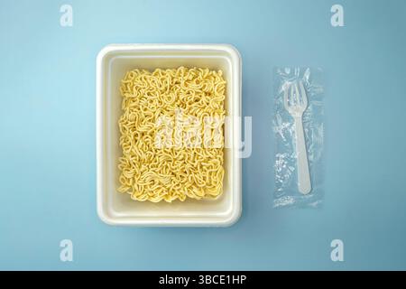 Boîte blanche de nouilles sur un fond bleu, nourriture rapide bon marché. Nouilles instantanées chinoises. Cuisine asiatique. vue de dessus Banque D'Images