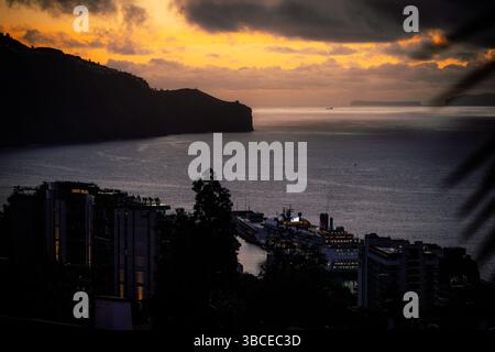 Coucher de soleil spectaculaire sur une ville côtière avec un bateau de croisière amarré dans le port Banque D'Images