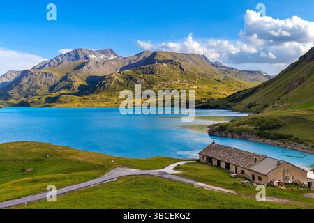 Une vue panoramique sur les eaux turquoises du lac du Mont Cenis entouré par les Alpes sous un ciel bleu avec des nuages blancs dans la région de Savoie. Banque D'Images
