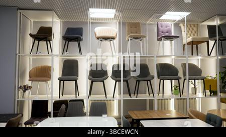 Grande variété de chaises modernes affichées sur les étagères dans un magasin de meubles bien éclairé, offrant diverses options de sièges pour les clients Banque D'Images