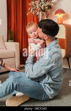 Un père aimant partage un moment délicieux en embrassant et embrassant son adorable petite fille, mettant en valeur la beauté de leur lien et la joie de Banque D'Images