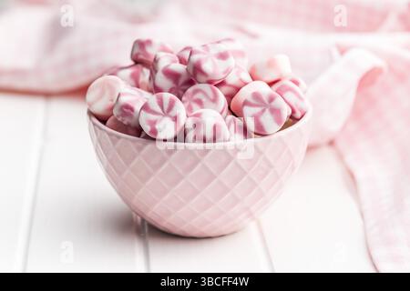 Bonbons rayés colorés dans un bol sur une table blanche. Banque D'Images