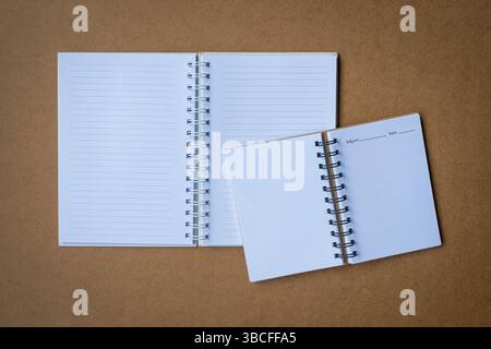 Deux cahiers à journaux ouverts sur le dessus du bureau en carton brun. Vue à plat ou de dessus. Banque D'Images