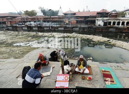 Astrologues assis au-dessus de la rivière Bagmati au temple Pashupatinath à Katmandou, Népal. Banque D'Images
