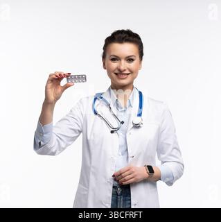 Photo de charmante femme attrayante un thérapeute spécialisé qualifié portent des pilules blanches de tenue de main de robe de médecin isolées sur fond blanc Banque D'Images