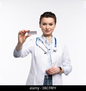 Photo de charmante femme attrayante un thérapeute spécialisé qualifié portent des pilules blanches de tenue de main de robe de médecin isolées sur fond blanc Banque D'Images