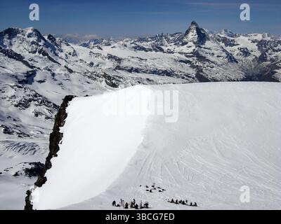 Beaucoup de skieurs de l'arrière-pays sur un haut plateau de sommet dans les Alpes suisses près de Zermatt avec une vue magnifique sur le Cervin derrière eux sur une belle w tardive Banque D'Images