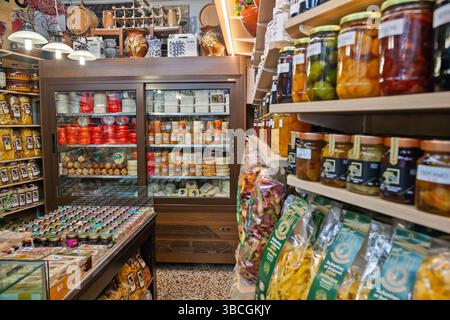 L'intérieur d'un traiteur grec traditionnel propose des fromages locaux, des pâtes faites à la main, des conserves, des herbes et des produits gastronomiques soigneusement disposés sur des étagères en bois Banque D'Images