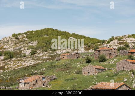 Cluster de cabanes traditionnelles en pierre avec des toits de tuiles rouges sur une colline ensoleillée à Picos de Europa, Asturies, Espagne Banque D'Images