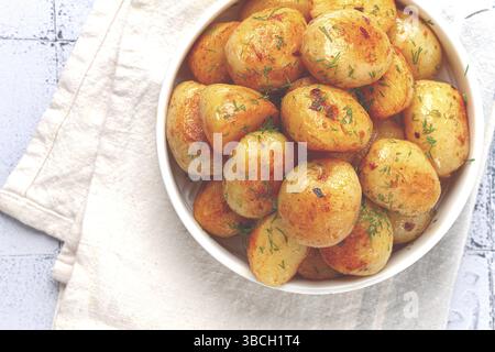 Pommes de terre nouvelles cuites au four, avec du beurre et de l'aneth, sur une assiette blanche, à la maison, pas de gens Banque D'Images