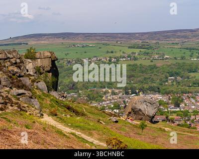 Les rochers de vache et de veau sur Ilkley Moor, Yorkshire, vus depuis le sentier de landes, avec la ville d'Ilkley dans la vallée en contrebas. ROYAUME-UNI Banque D'Images