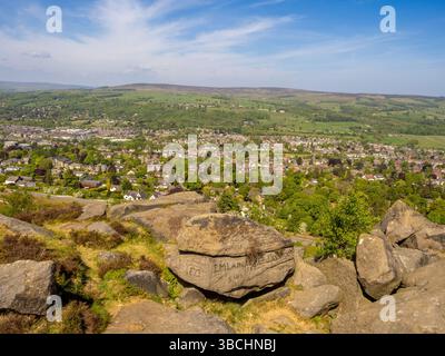 Vue sur Ilkley depuis les rochers de vache et de veau, avec graffiti sculptés historiques visibles sur les rochers du premier plan. West Yorkshire. ROYAUME-UNI Banque D'Images