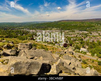 Vue sur Ilkley depuis les rochers de vache et de veau, avec graffiti sculptés historiques visibles sur les rochers du premier plan. ROYAUME-UNI Banque D'Images