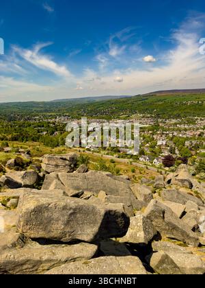 Vue sur Ilkley depuis les rochers de vache et de veau, avec graffiti sculptés historiques visibles sur les rochers du premier plan. West Yorkshire. ROYAUME-UNI Banque D'Images